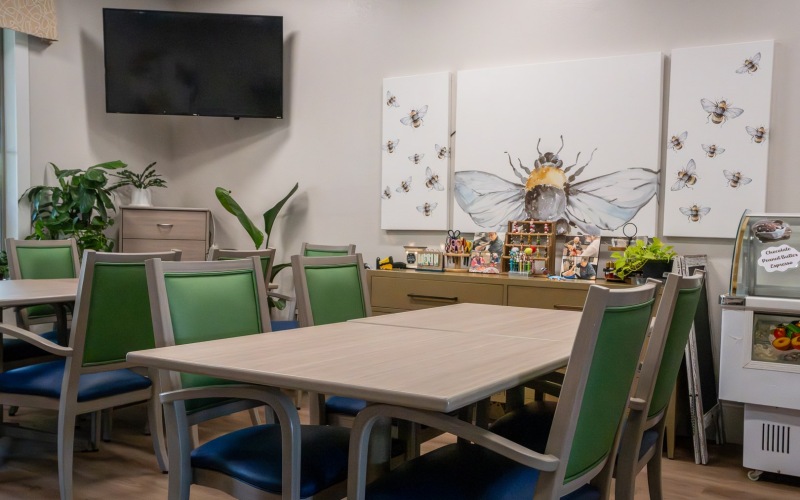 a room with tables and chairs and tv hanging on the wall