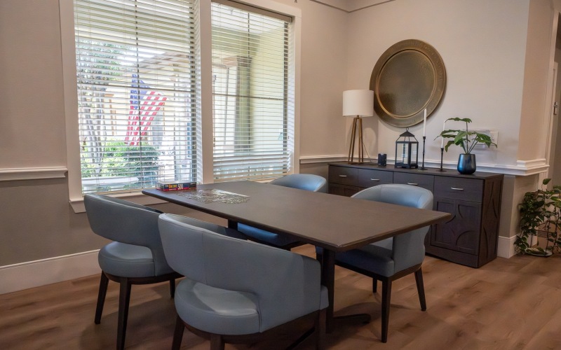 chairs and a table with a puzzle on it in a room with a window